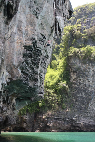 Rock climber scaling steep limestone cliff face