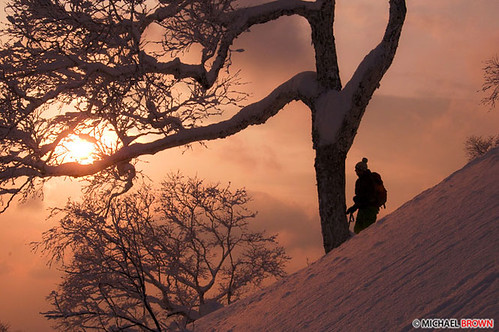 Sunset silhouette of a person skiing uphill