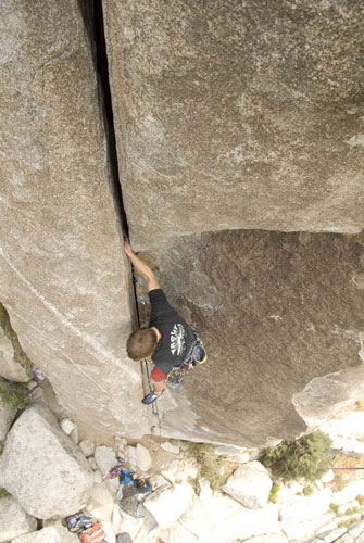 Rock climber ascending steep granite crack face