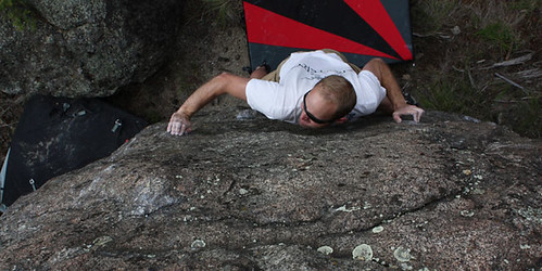 Man bouldering on rock with climbing gear