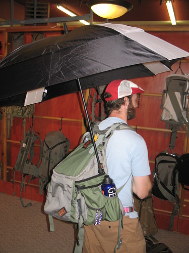 Man with backpack and umbrella indoors shopping
