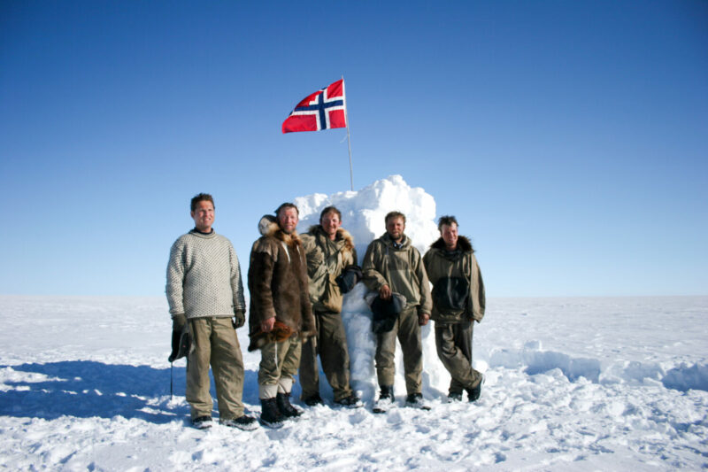 Group of explorers around a self-built cairn at the South Pole