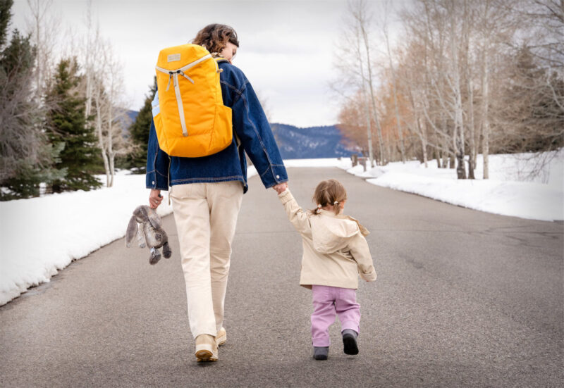 Mother with a backpack holding hands with a young girl