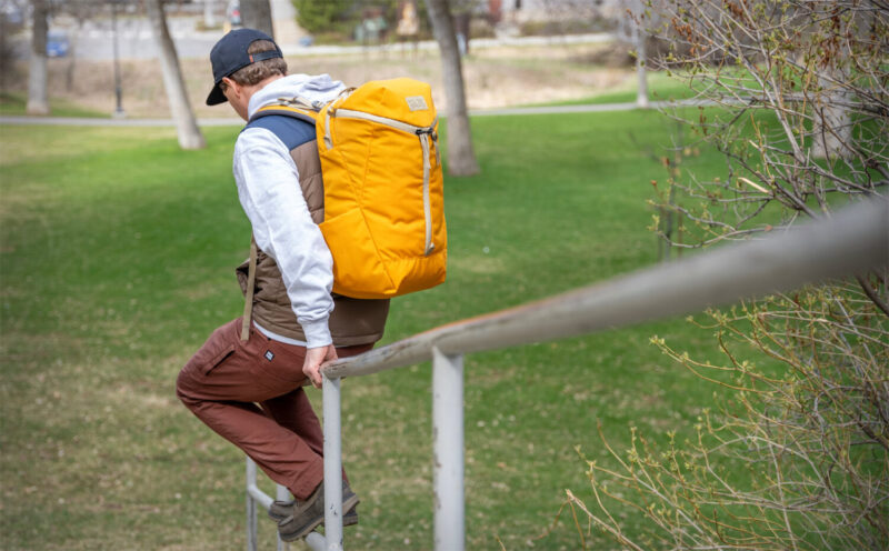Man with backpack sitting on a handrail outside