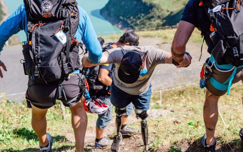 Disabled hiker being helped up a hill